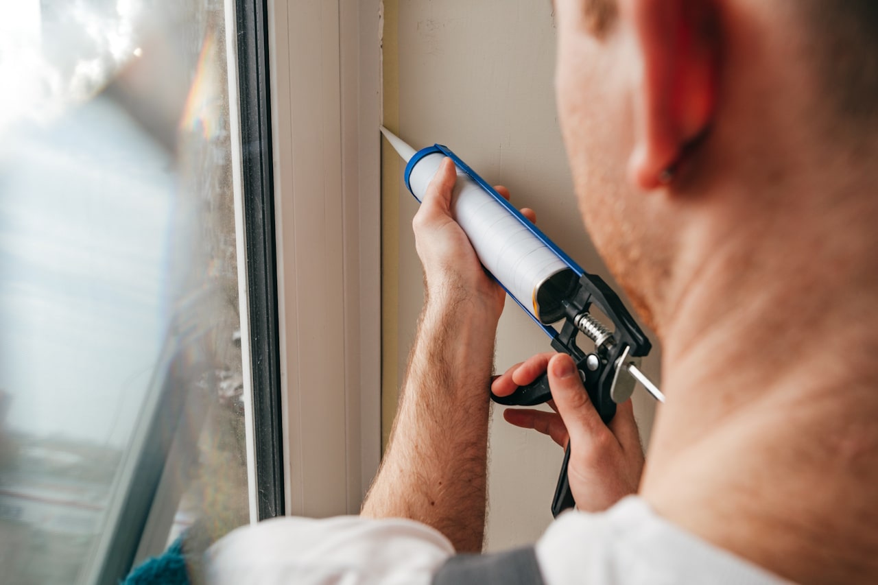 Worker sealing cracks around a basement window to prevent water leaks
