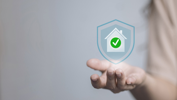 Home security shield with check mark in hand, symbolizing home protection