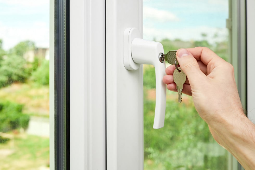 Man locking a window with a key, demonstrating secure window locks